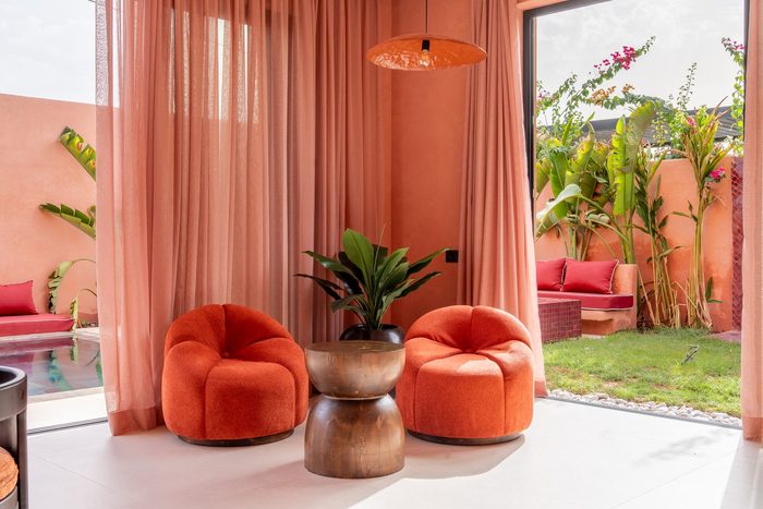 Fauteuils bouclé orange et voilages face au jardin