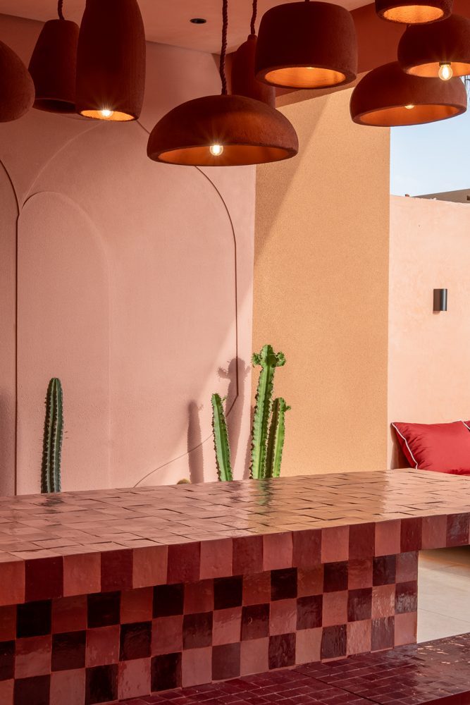 Comptoir en zellige damier sous des suspensions en terre cuite, cactus