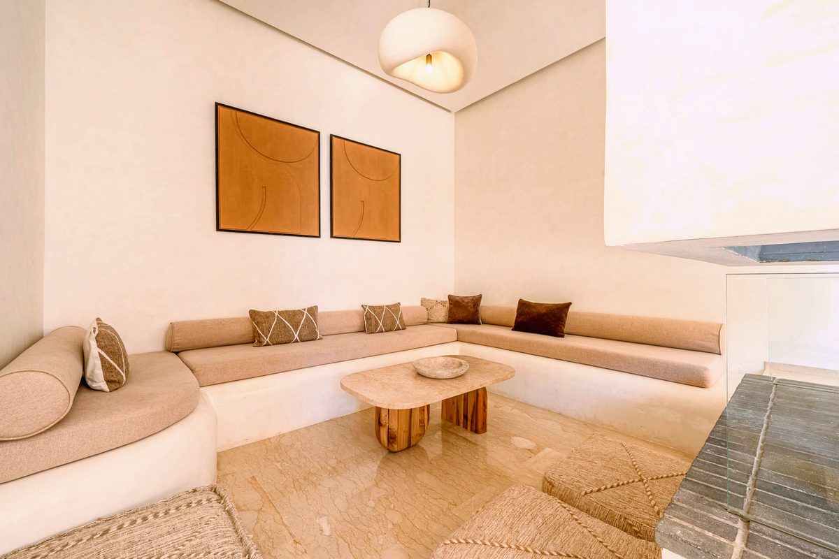 The living room at Villa Camélia, linen daybeds and a travertine floor